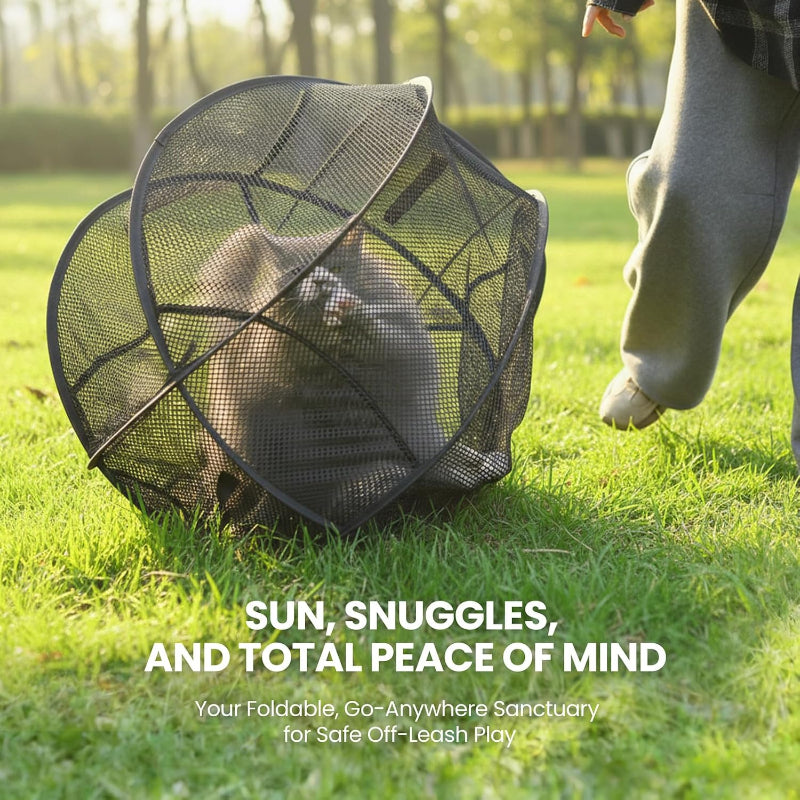 A black foldable mesh pet enclosure sits on grass in a sunny outdoor park setting, with part of a person's leg visible nearby and promotional text overlaid at the bottom.