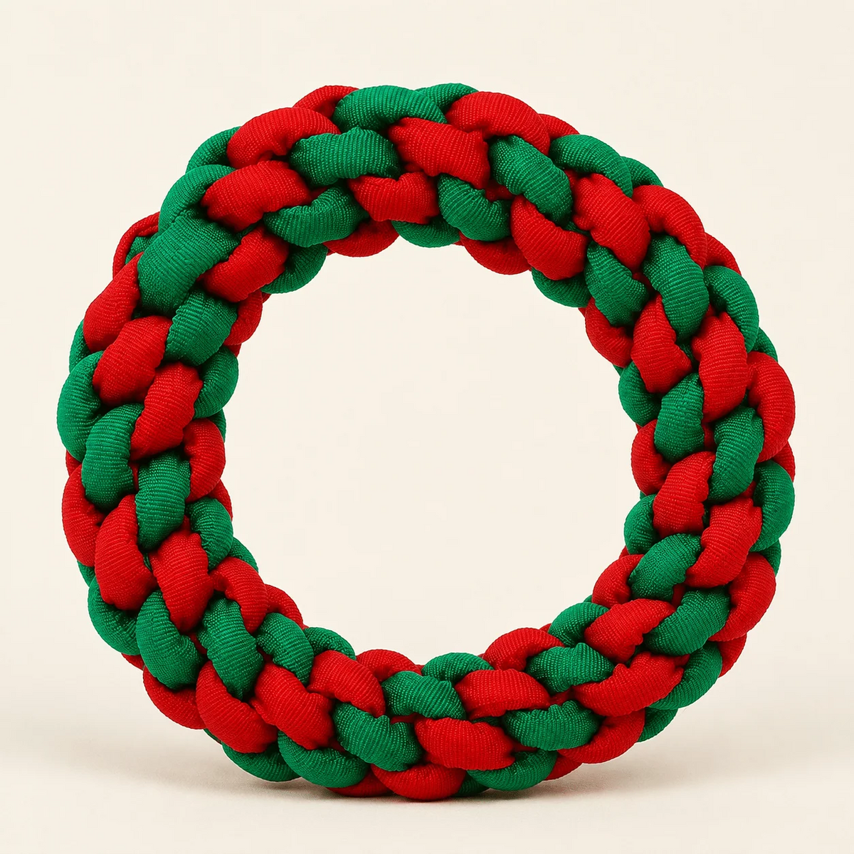A braided circular wreath made from alternating red and green ribbed fabric, photographed against a plain light beige background.